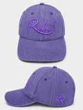 A purple washed cotton baseball cap shown from the front and side angles against a light gray background. The front features the word 'Rebel' embroidered in purple script, and the side displays a small Anarchy inspired embroidered 'R' logo.