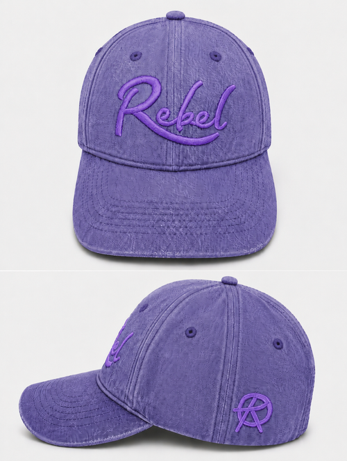 A purple washed cotton baseball cap shown from the front and side angles against a light gray background. The front features the word 'Rebel' embroidered in purple script, and the side displays a small Anarchy inspired embroidered 'R' logo.