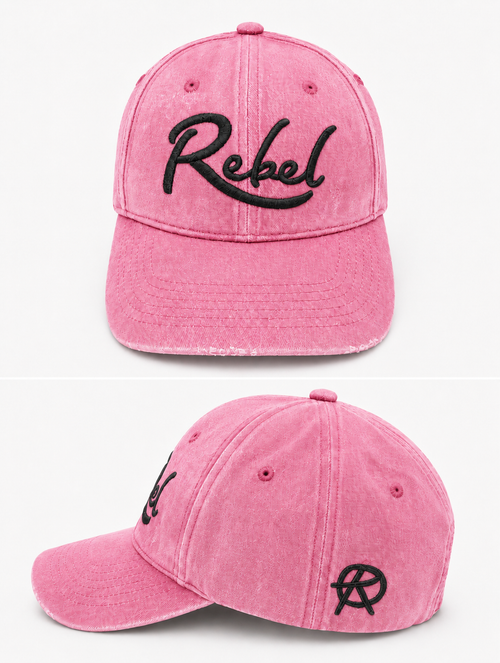 A pink washed cotton baseball cap shown from the front and side angles against a light gray background. The front features the word 'Rebel' embroidered in black script, and the side displays a small Anarchy inspired embroidered 'R' logo.