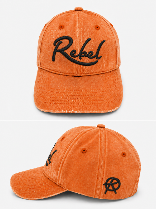 An orange washed cotton baseball cap shown from the front and side angles against a light gray background. The front features the word 'Rebel' embroidered in black script, and the side displays a small Anarchy inspired embroidered 'R' logo.