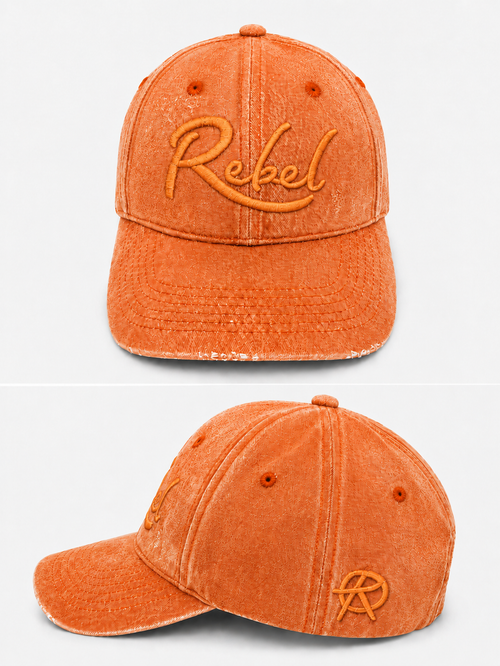 An orange washed cotton baseball cap shown from the front and side angles against a light gray background. The front features the word 'Rebel' embroidered in orange script, and the side displays a small Anarchy inspired embroidered 'R' logo.