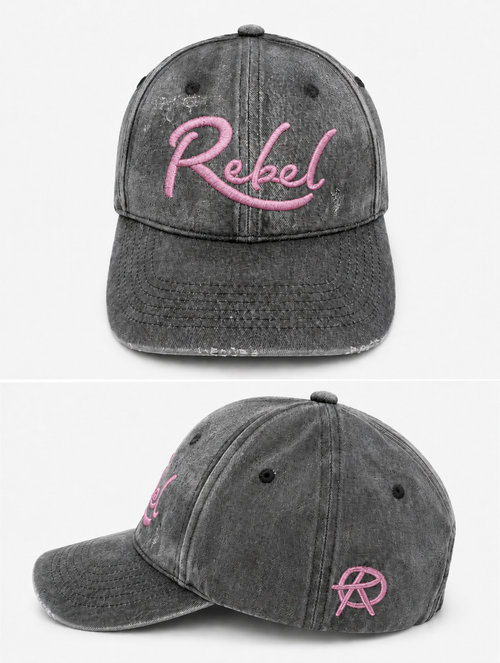 A black washed cotton baseball cap shown from the front and side angles against a light gray background. The front features the word 'Rebel' embroidered in pink script, and the side displays a small Anarchy inspired embroidered 'R' logo.